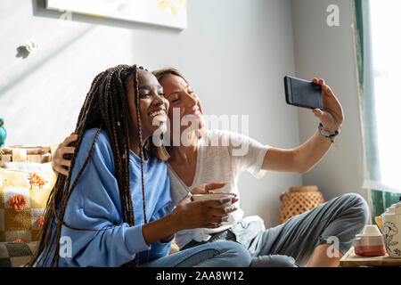 Coppia di amici prendendo un Selfie/chiamata video a casa Foto Stock