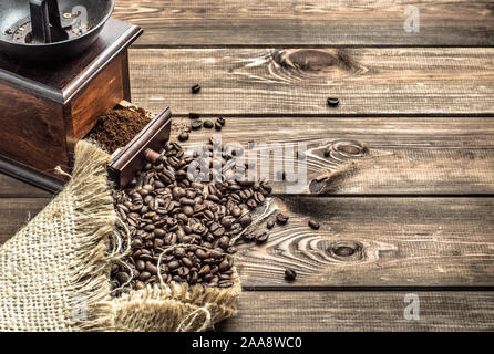 Coffee Mill e fagioli arrosto nel sacco di tela su legno sfondo rustico Foto Stock