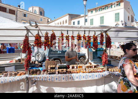 Sineu, Spagna. 09oct, 2019. Un commerciante offre i peperoni, peperoncini, le e inceppamento al mercato in Sineu, mentre un visitatore al mercato passeggiate passato il suo stand. Il mercato di Sineu attrae ogni mercoledì i turisti da tutte le località di vacanza in Mallorca. Credito: Stephan Schulz/dpa-Zentralbild/ZB/dpa/Alamy Live News Foto Stock