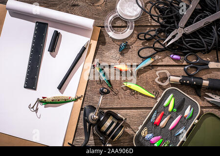 Accessori per la pesca sullo sfondo di legno. Aspo, la lenza, float, net ganci, esche artificiali per la pesca. Vista dall'alto. Ancora in vita. Spazio di copia Foto Stock