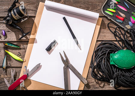 Accessori per la pesca sullo sfondo di legno. Aspo, la lenza, float, net ganci, esche artificiali per la pesca. Vista dall'alto. Ancora in vita. Spazio di copia Foto Stock