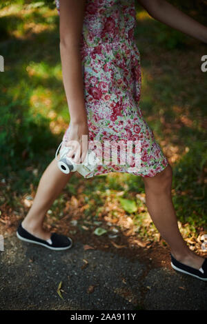 Adorabile ragazza preteen tenendo la fotocamera istantanea e passeggiate nel parco verde Foto Stock