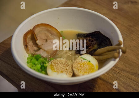 Una ciotola di tradizionale giapponese Ramen di maiale minestra con funghi Enoki, medio-uova sode, scalogno, alghe e carne di maiale Foto Stock
