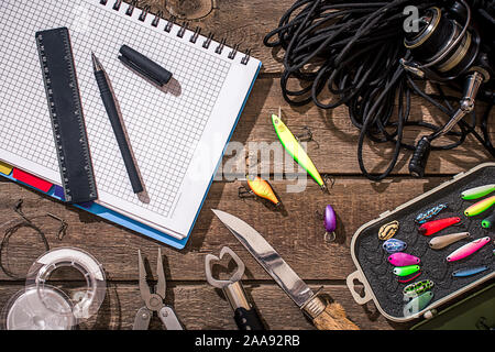 Accessori per la pesca sullo sfondo di legno. Aspo, la lenza, float, net ganci, esche artificiali per la pesca. Vista dall'alto. Ancora in vita. Spazio di copia Foto Stock