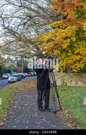 Stuart Ratcliffe, reporter per la BBC guardare ad est per filmare un pezzo attorno alla Croce di Eleanor, Northampton, Regno Unito Foto Stock