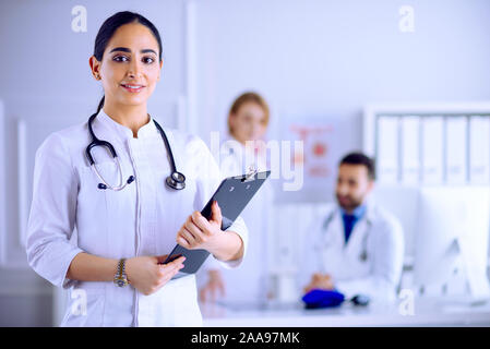 Medico arabo in piedi nella parte anteriore del suo team in ospedale Foto Stock