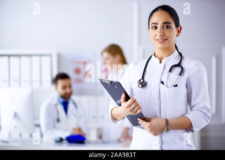 Medico arabo in piedi nella parte anteriore del suo team in ospedale Foto Stock