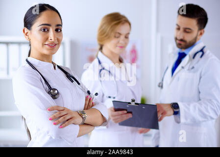 Attraente femmina medico arabo sorridente in parte anteriore del materiale medico in ospedale Foto Stock