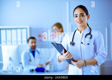 Medico arabo in piedi nella parte anteriore del suo team in ospedale Foto Stock