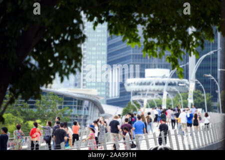 (Immagine sfocati) folla indistinta di persone locali e turisti a piedi su un ponte in Singapore. Foto Stock