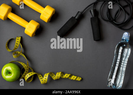 Piano di allenamento con fitness cibo e attrezzature sportive su sfondo grigio, vista dall'alto. Copia dello spazio. Still Life Foto Stock