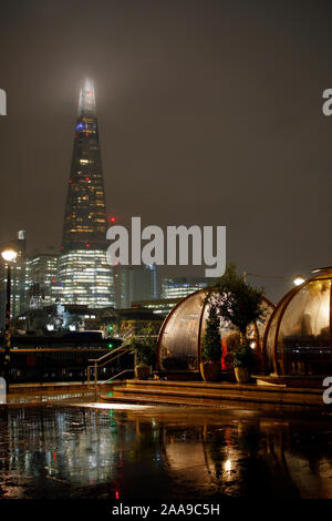 Le cialde da pranzo presso la Coppa club il Tower Bridge di Londra e il coccio su un umido di notte. Foto Stock