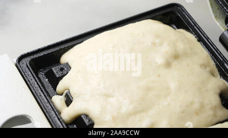 Un waffle fatti.Waffle pastella essendo versata su una piastra per i waffle Foto Stock