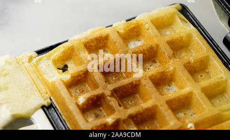 Un waffle fatti in casa finito di cottura su una piastra per i waffle Foto Stock