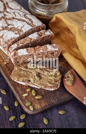 Pane di segale fresco fatto in casa con semi di zucca fatti in casa spalmati su un asse di legno Foto Stock