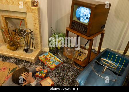 Un ragazzo disteso sul pavimento guardando un vecchio televisore in un 1960 soggiorno o salotto Foto Stock