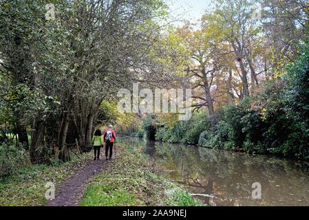 Il fiume Wey navigazione a Byfleet con due escursionisti sulla strada alzaia in un colorato autunno il giorno Surrey in Inghilterra REGNO UNITO Foto Stock