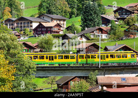 Lauterbrunnen, Svizzera - 10 Ottobre 2019: Alpina case di legno nelle Alpi Svizzere villaggio in autunno e Wengernalpbahn treno Foto Stock