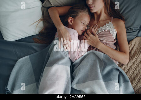 Madre dormire abbracciando con figlia piccola ragazza. La famiglia e la festa della mamma concetto. Foto Stock