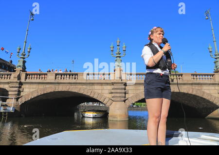 Un tour guida fornisce informazioni ai turisti in gita in barca in Paddan città di Göteborg, Svezia, mentre la gente guarda su da un ponte. Foto Stock