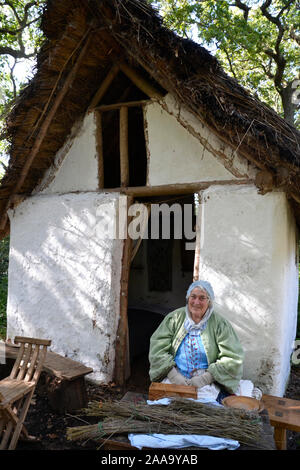 Donna seduta fuori casa a Little Woodham 17th Century Village, Gosport, Hampshire, Regno Unito Foto Stock