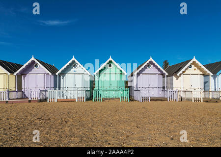 Una fila di color pastello spiaggia capanne a West Mersea. Mersea Island, Essex, Regno Unito. Foto Stock