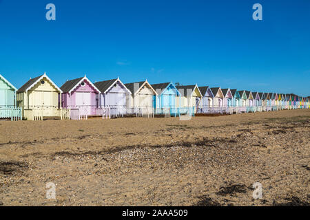 Una fila di color pastello spiaggia capanne a West Mersea. Mersea Island, Essex, Regno Unito. Foto Stock