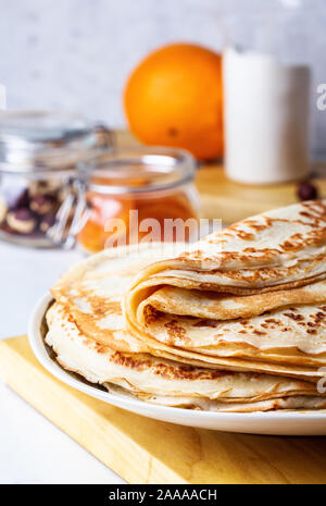 Frittelle di sottile su bianco tavolo rustico, ingredienti, rendendo blini, cucina domestica e crepes Foto Stock