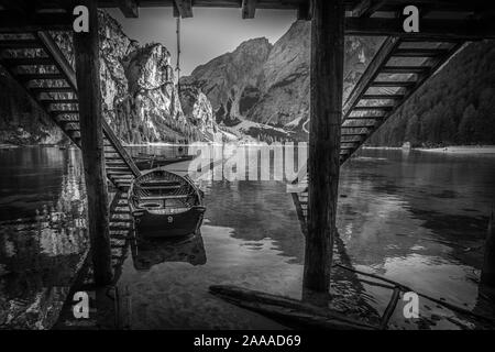 Effetto bianco e nero di barche a remi ormeggiate sul pontile in un lago Foto Stock