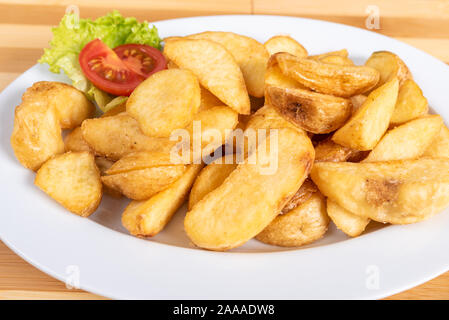 Patate fritte le fette su un piatto. Con verdi. Foto Stock