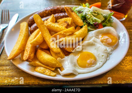 Un tipico pub inglese pasto di salsiccia, uova e patatine. Foto Stock