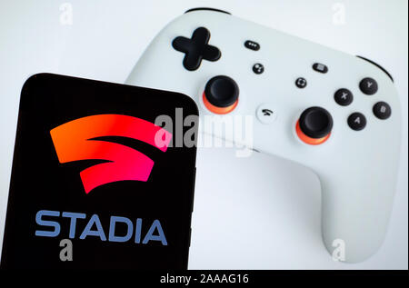 Stadi logo su una schermata dello smartphone e bianco Google stadi controller visto sullo sfondo sfocato. Foto Stock