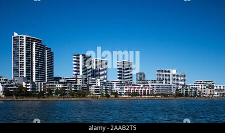 Grandi case di waterfront, appartamento condominiums in comunità suburbane sul porto con viale alberato pedonale, cielo blu in background Foto Stock