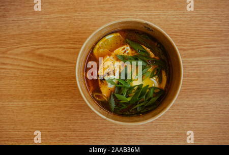 Zuppa asiatica in un bicchiere di carta sul tavolo in legno Foto Stock