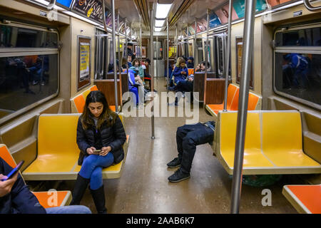 New York, Stati Uniti d'America, 9 novembre 2019. Ai passeggeri di utilizzare i loro telefoni cellulari ignorando un povero uomo dorme nella metropolitana di New York City. Credito: Foto Stock