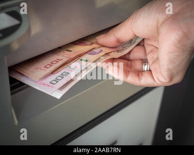 Close-up mano prelevare denaro, le banconote Thai baht dal bancomat in Thailandia. Lato Ricezione di denaro contante dai bancomat. Foto Stock