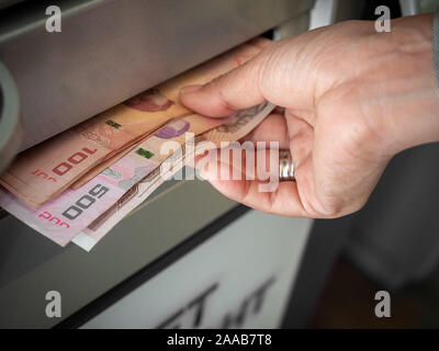 Close-up mano prelevare denaro, le banconote Thai baht dal bancomat in Thailandia. Lato Ricezione di denaro contante dai bancomat. Foto Stock