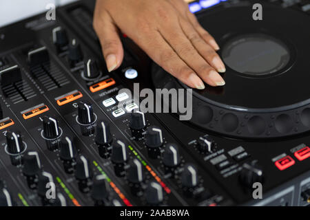 Le mani di DJ mixare brani su professional mixer audio.gli anelli alla moda sulle dita di una ragazza disc jockey riproduzione di musica.Closeup,le manopole e i regolatori di Foto Stock