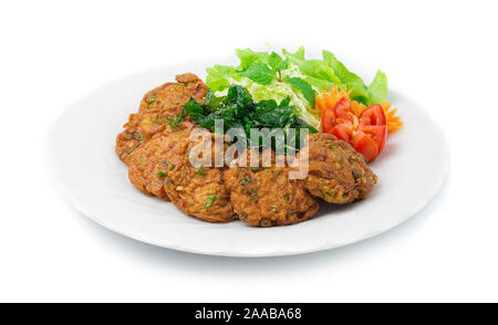 Thai torta di pesce pasta di peperoncino fritti con erbe e croccante di basilico tailandese. Il cibo tailandese stile piatto decorare con scolpite le carote forma di fiore e lato di pomodoro Foto Stock