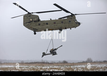 Un CH-47 elicottero Chinook decolla portando un M119A3 obice dopo i soldati assegnati al 2° Battaglione, xv campo reggimento di artiglieria, 2° Brigata Team di combattimento, decimo Montagna divisione eseguito un air ASSAULT SLING operazione di carico durante il livello di carica della batteria gunnery certificazione, Novembre 19, 2019, a Fort Drum, New York. (U.S. Foto dell'esercito da Staff Sgt. Paige Behringer) Foto Stock