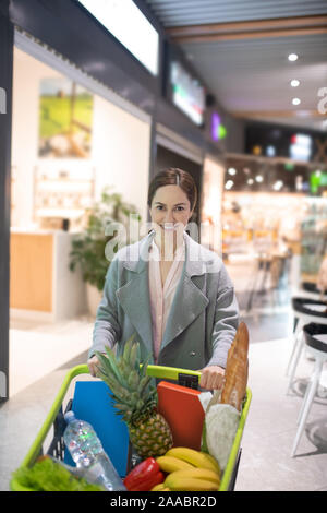 Imprenditrice lasciando supermercato dopo l'acquisto di generi alimentari di sera Foto Stock