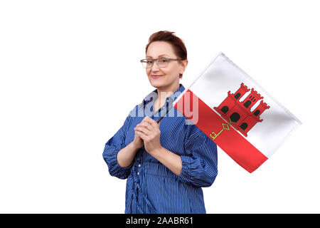 Bandiera di Gibilterra. Donna che mantiene bandiera di Gibilterra. Bel ritratto di mezza età lady 40 50 anni tenendo un grande bandiera isolati su sfondo bianco. Foto Stock