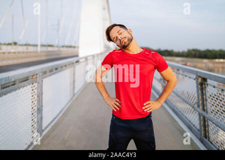 L'uomo runner prendendo una pausa durante il corso di formazione all'esterno. Appoggio del pareggiatore dopo l'esecuzione. Foto Stock