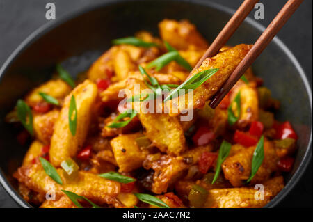 Baby mais secco Manchurian sembra Schezwan Baby mais in vaso nero in ardesia scuro dello sfondo. Baby Corn Manchurian - è indo cucina cinese piatto wit Foto Stock