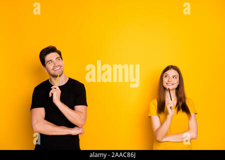 Foto di allegro positivo bella carino affascinante piuttosto giovane azienda penne vestita di nero t-shirt toothily sorridente cercando nello spazio vuoto di un accoppiamento di Foto Stock