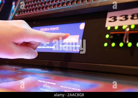 Il movimento di persone premendo il pulsante riscattare sulle slot machine Casino interno Foto Stock
