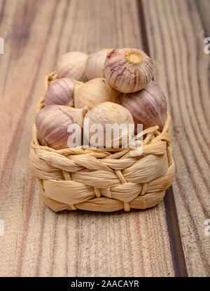 A pochi capi di giovani aglio in un cesto di vimini su un sfondo di legno. Raccolto autunnale. L'agricoltura moderna. Close up Foto Stock