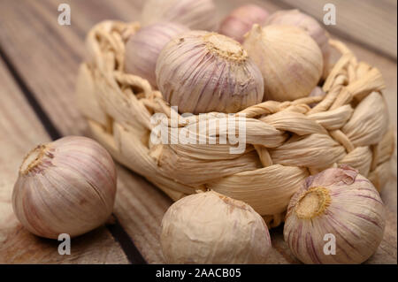 A pochi capi di giovani aglio in un cesto di vimini su un sfondo di legno. Raccolto autunnale. L'agricoltura moderna. Close up Foto Stock