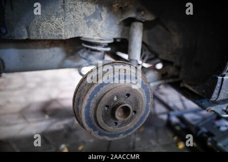 Profondità di campo (messa a fuoco selettiva) immagine con un arrugginito mozzo di ruota posteriore di una vecchia auto. Foto Stock