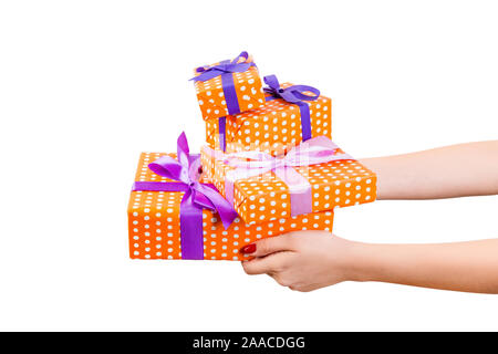 Donna mani dare gruppo incartato di Natale o di altre vacanze presente fatti a mano in carta arancione con nastro di colore viola. Isolato su sfondo bianco, vista dall'alto Foto Stock